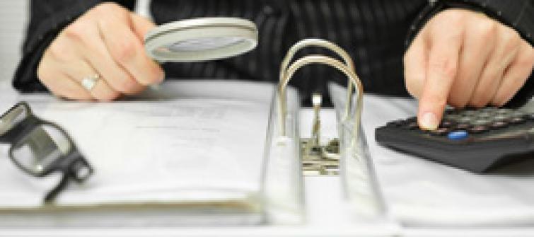 Business man using magnifying glass to scan report.