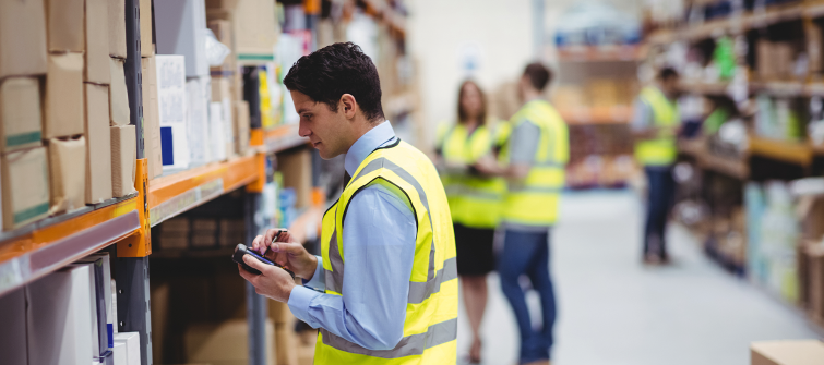 Employees in a warehouse using tools to track a company’s demand forecasting