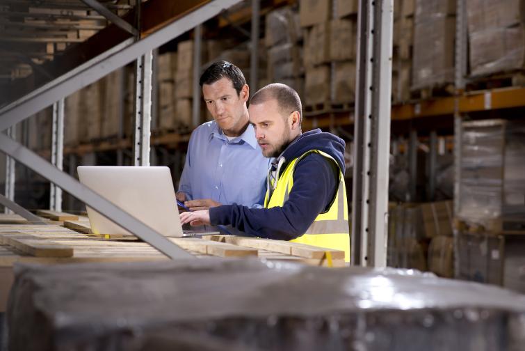 a businessman and a warehouse manager checking inventory levels on a laptop