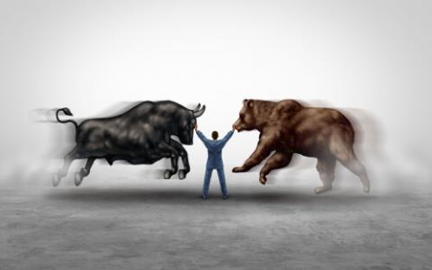 Stock broker between a charging bull and charging bear.