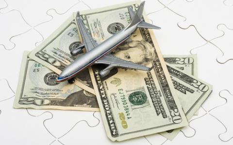 Plane on a pile of money, representing travel expenses