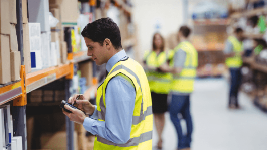 Employees in a warehouse using tools to track a company’s demand forecasting