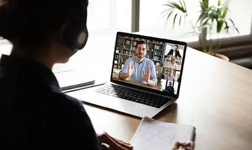 E-learning via virtual application, videocall video conferencing activity, colleagues working together concept. Pc screen view over woman shoulder, listen tutor gain new knowledge noting information