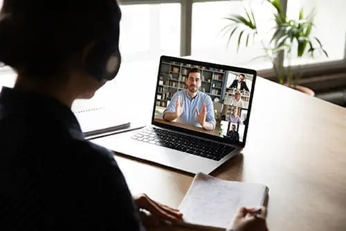 E-learning via virtual application, videocall video conferencing activity, colleagues working together concept. Pc screen view over woman shoulder, listen tutor gain new knowledge noting information
