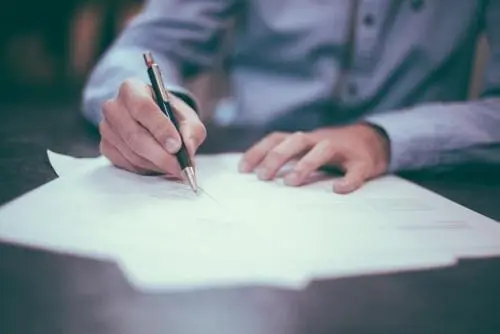 man in business clothes signing a document
