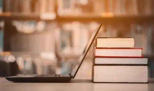 laptop and stack of books on a table