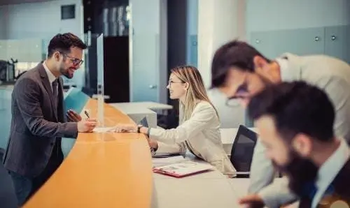 man signing a form at a receptionists desk
