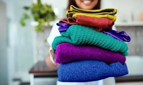 woman holding a stack of folded colorful clothes