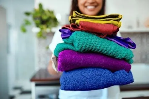 woman holding a stack of folded colorful clothes