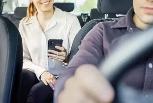 woman on smartphone in backseat of a car