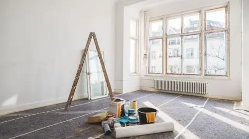 empty room under construction with a ladder and cans of paint