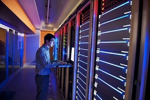 Modern interior of server room in datacenter. IT Engineer in Action Configuring Servers