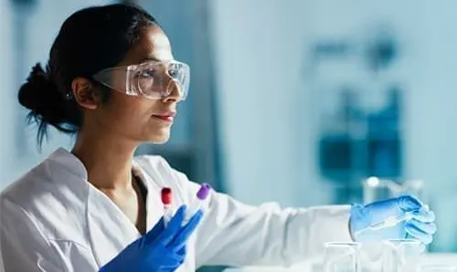 doctor in a lab holding test tubes with goggles on
