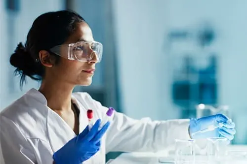 doctor in a lab holding test tubes with goggles on