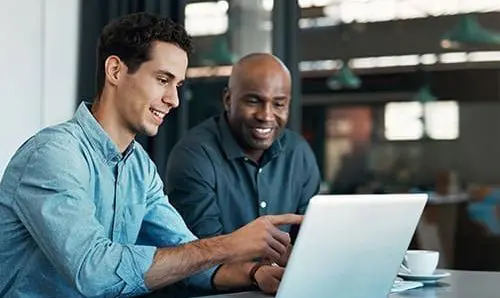 two business professionals looking at a laptop screen and smiling