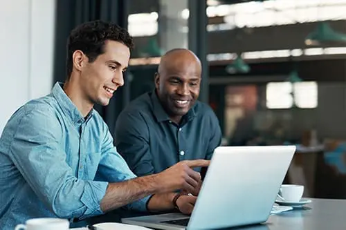 two business professionals looking at a laptop screen and smiling