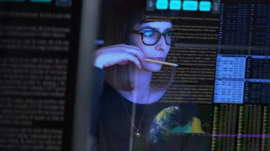 Stock image of a beautiful young woman studying a see through computer screen and contemplating.