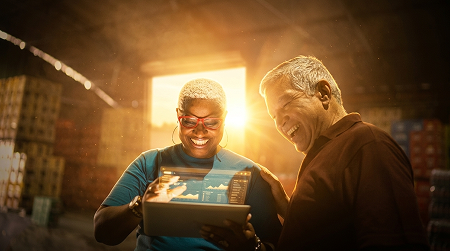 Woman and man both smiling, look at a tablet together