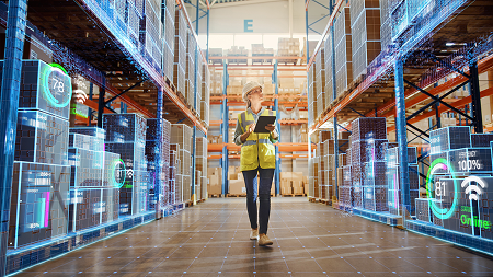 A woman wearing a yellow safety vest walks in a warehouse holding a clipboard. A blue grid and data is superimposed on the image.