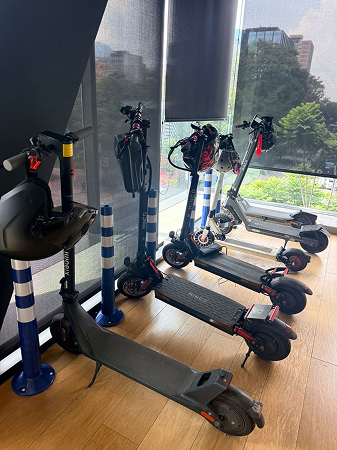 Four scooters equipped with helmets charge inside the Coupa office building