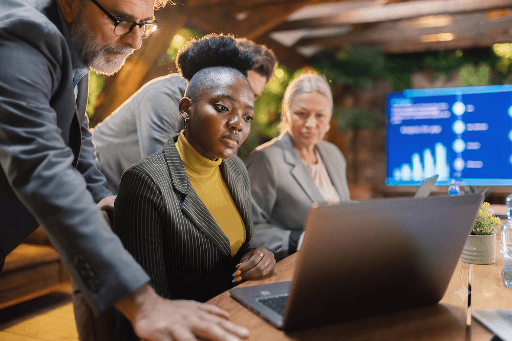 A diverse team of professionals reviewing information on a laptop together.