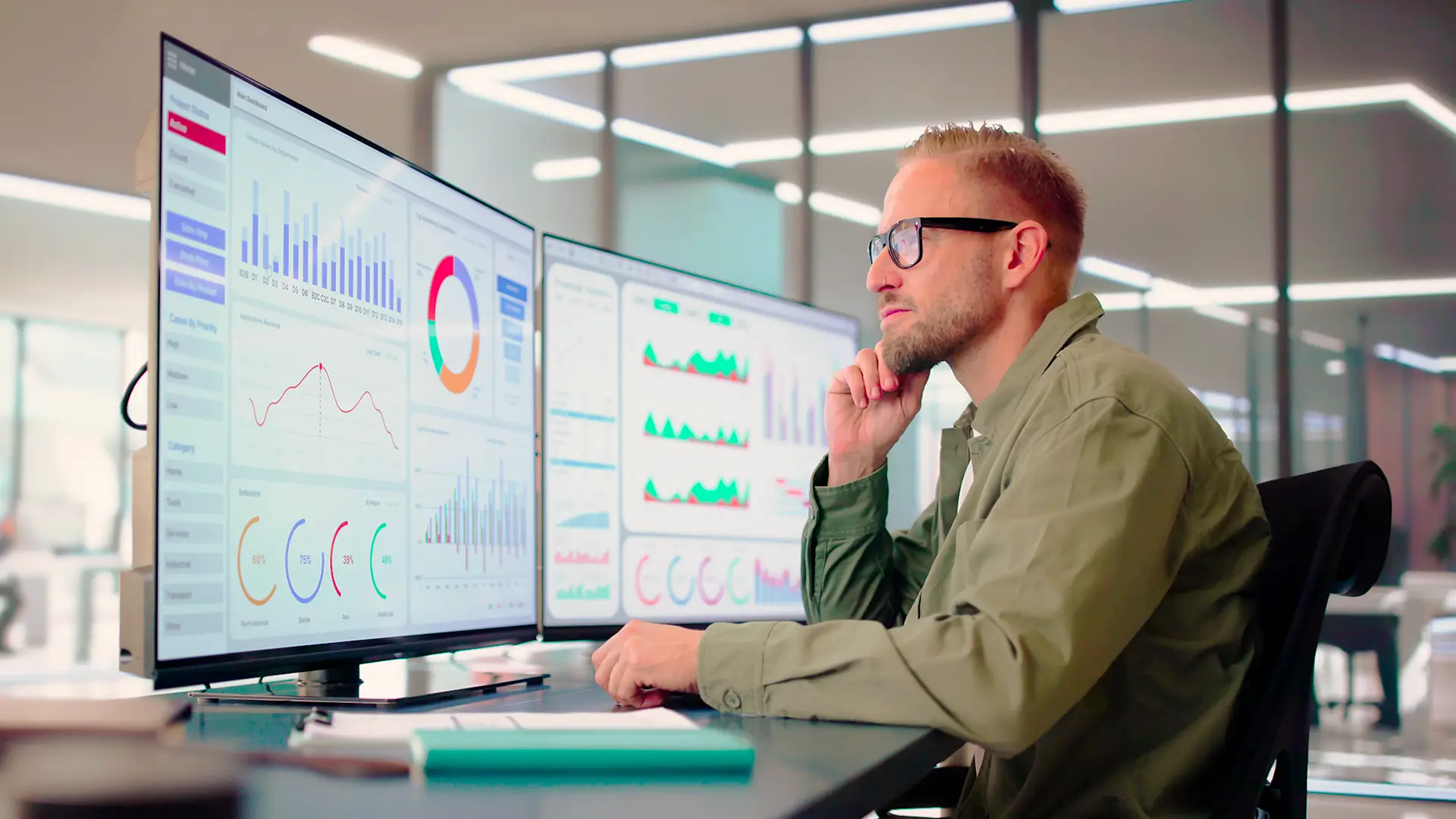 Man reviewing graphs and charts on a workstation screen.