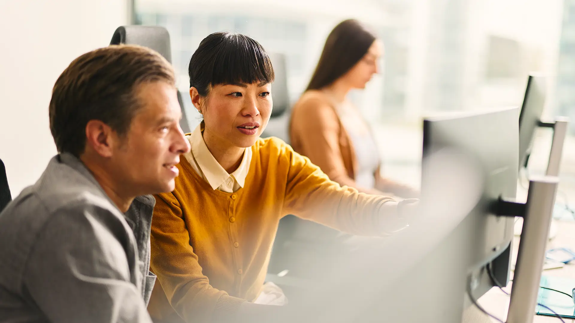 Woman showing a colleague information on a workstation.